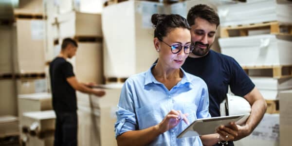 Man and woman looking at tablet in warehouse: Improving Supply Chain Efficiency with Data